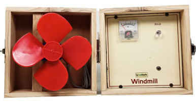 A wooden windmill model kit with two compartments. The left side contains a red four-blade rotor connected to a motor. The right side features a panel with a voltmeter, a small LED bulb, and a labeled section reading "Windmill" by Labkafe.